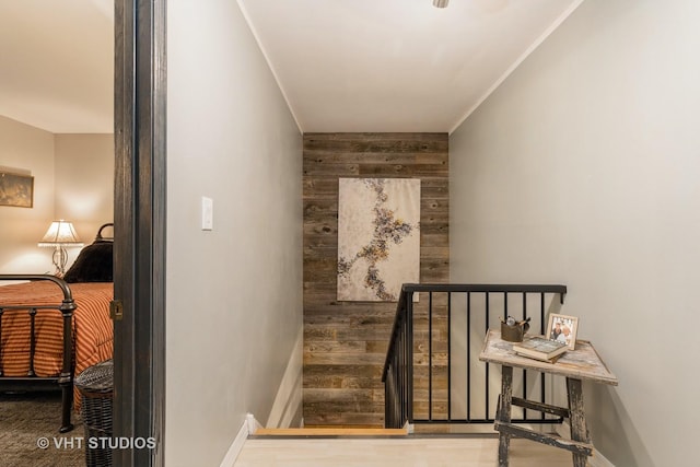 stairway featuring ornamental molding and wood walls