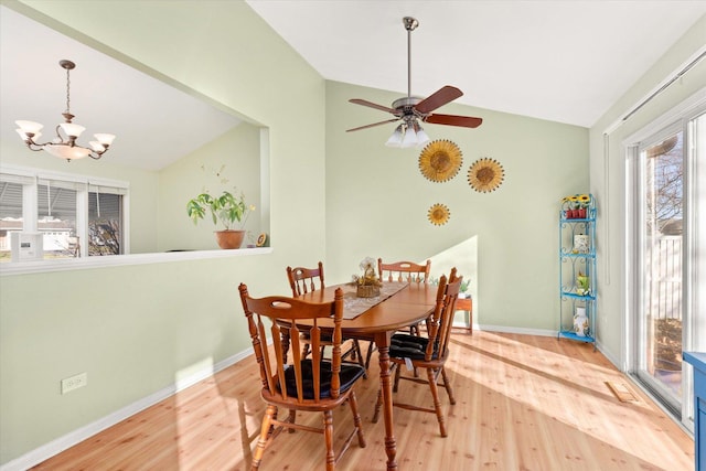 dining room featuring ceiling fan with notable chandelier, vaulted ceiling, and hardwood / wood-style flooring