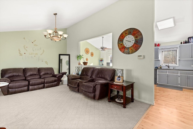 living room with hardwood / wood-style floors, ceiling fan with notable chandelier, sink, and vaulted ceiling