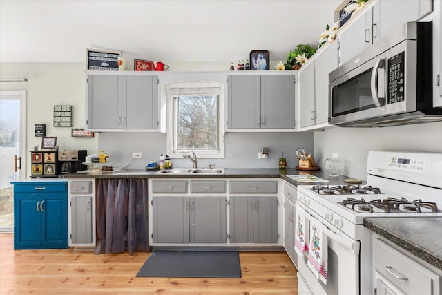 kitchen featuring gray cabinets, sink, light wood-type flooring, and white gas range oven