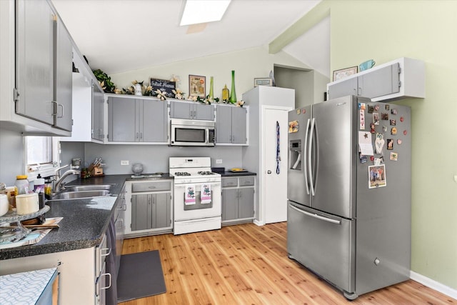 kitchen with sink, light hardwood / wood-style flooring, vaulted ceiling with beams, gray cabinets, and stainless steel appliances