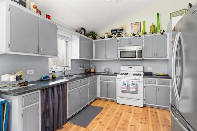 kitchen featuring gray cabinetry, sink, light hardwood / wood-style flooring, lofted ceiling, and appliances with stainless steel finishes