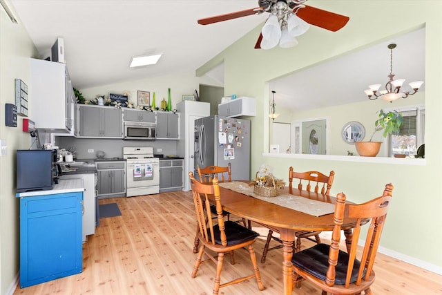 dining area featuring ceiling fan with notable chandelier, light hardwood / wood-style flooring, and vaulted ceiling