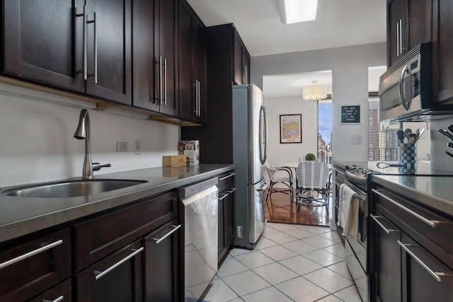 kitchen featuring dark brown cabinets, sink, light tile patterned floors, and stainless steel appliances