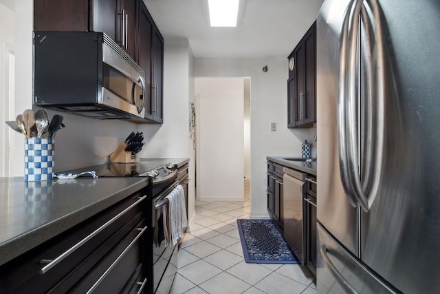 kitchen with appliances with stainless steel finishes, light tile patterned floors, and dark brown cabinets