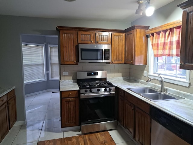 kitchen with decorative backsplash, sink, light tile patterned flooring, and appliances with stainless steel finishes