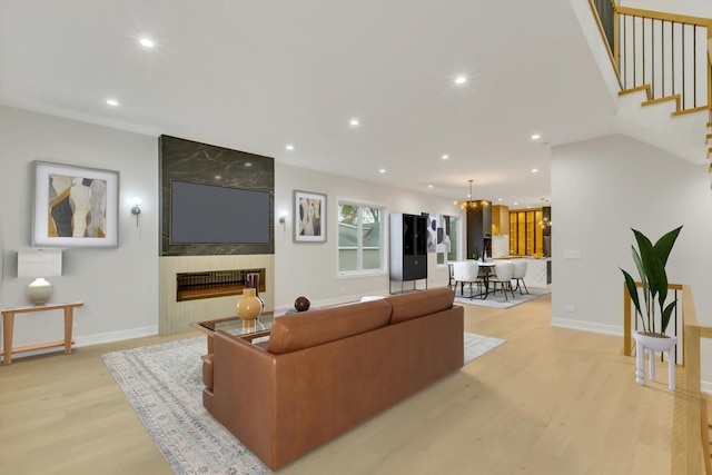 living room featuring light hardwood / wood-style flooring, a fireplace, and an inviting chandelier