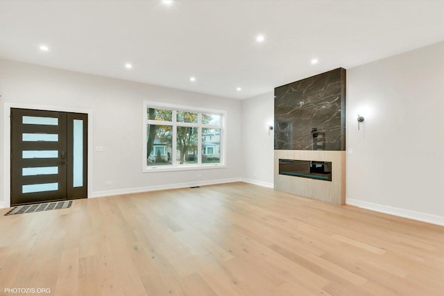 unfurnished living room with light hardwood / wood-style floors and a large fireplace