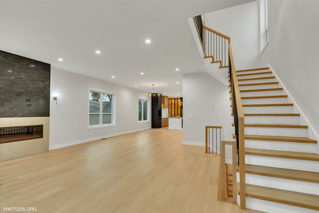 unfurnished living room featuring a chandelier, a fireplace, and light hardwood / wood-style floors