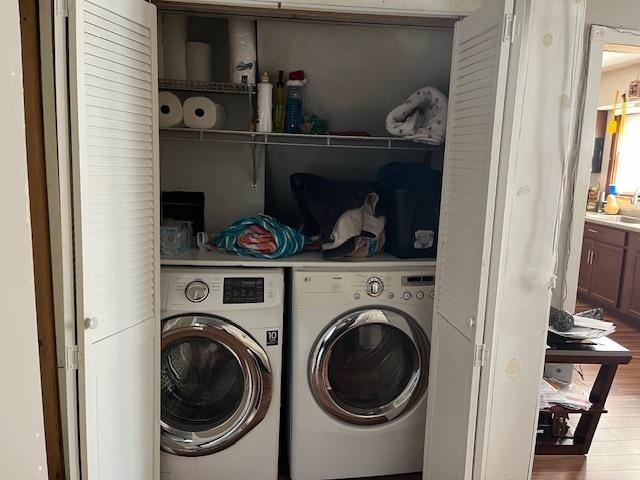 washroom with sink, light hardwood / wood-style flooring, and washing machine and clothes dryer