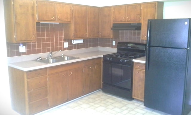 kitchen featuring black appliances, decorative backsplash, and sink