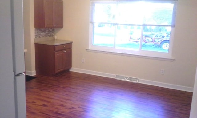 unfurnished dining area with a wealth of natural light and dark hardwood / wood-style flooring