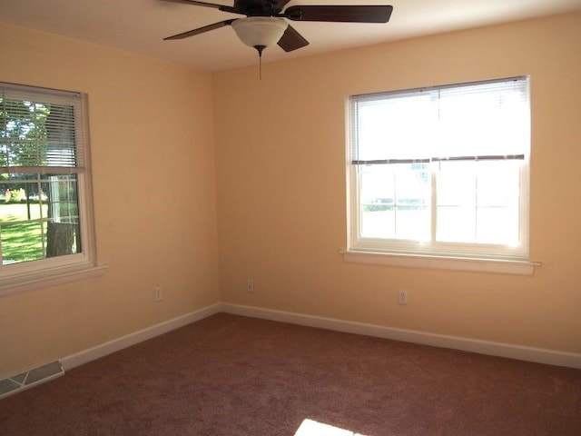 carpeted spare room featuring plenty of natural light and ceiling fan