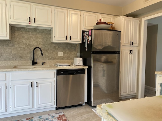 kitchen with stainless steel appliances, tasteful backsplash, sink, and white cabinets