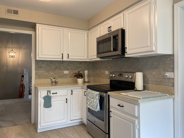 kitchen with tasteful backsplash, appliances with stainless steel finishes, and white cabinets