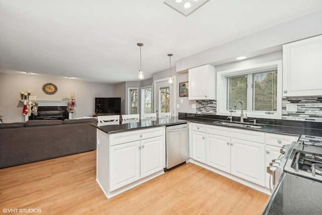 kitchen featuring hanging light fixtures, sink, kitchen peninsula, appliances with stainless steel finishes, and white cabinetry