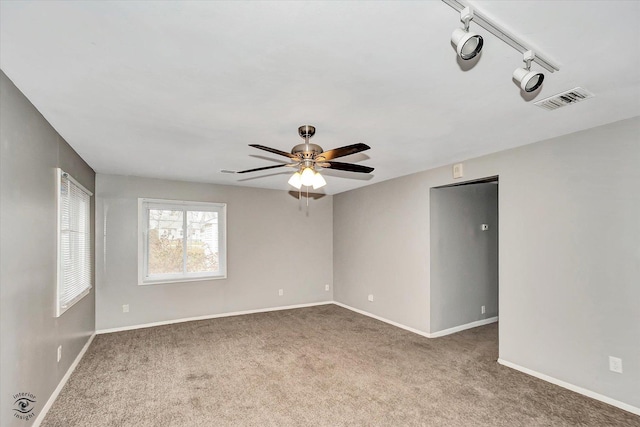 carpeted spare room featuring track lighting and ceiling fan