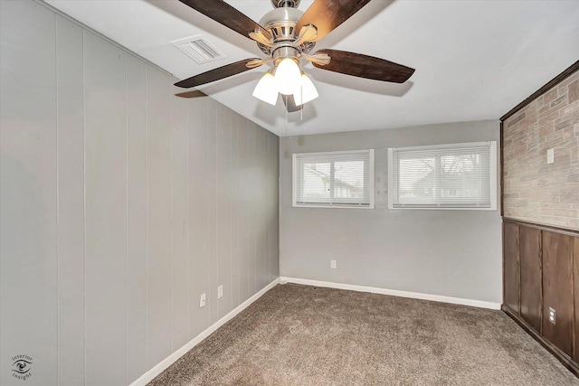 unfurnished room with carpet floors, ceiling fan, and wood walls