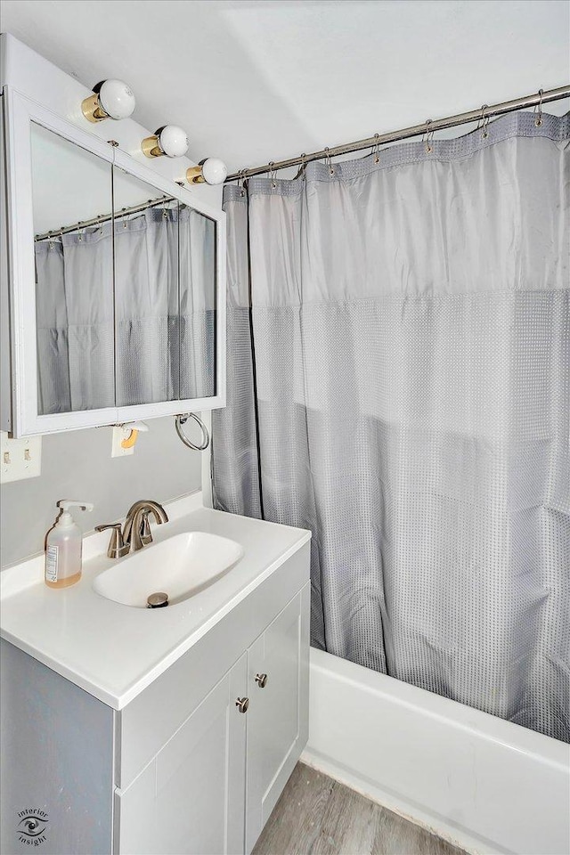 bathroom with hardwood / wood-style floors, vanity, and shower / tub combo with curtain