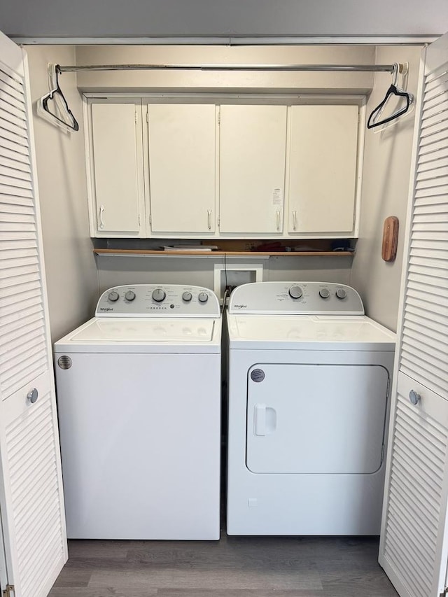 clothes washing area featuring washer and dryer, cabinets, and dark wood-type flooring