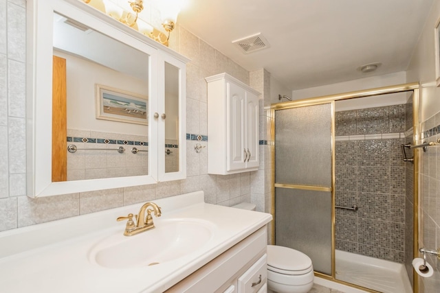 bathroom featuring vanity, a shower with door, toilet, and tile walls