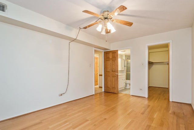 unfurnished bedroom with ceiling fan, light hardwood / wood-style flooring, ensuite bathroom, a walk in closet, and a closet