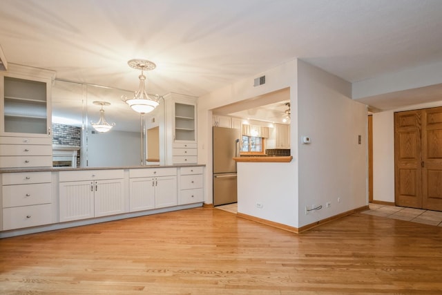 kitchen featuring white cabinetry, stainless steel fridge, pendant lighting, and light hardwood / wood-style floors