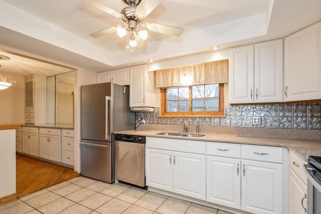 kitchen featuring a raised ceiling, white cabinetry, sink, and appliances with stainless steel finishes