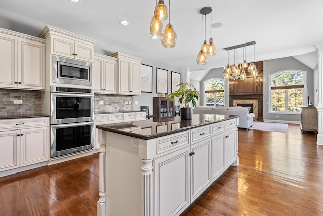 kitchen featuring appliances with stainless steel finishes, pendant lighting, backsplash, and a kitchen island