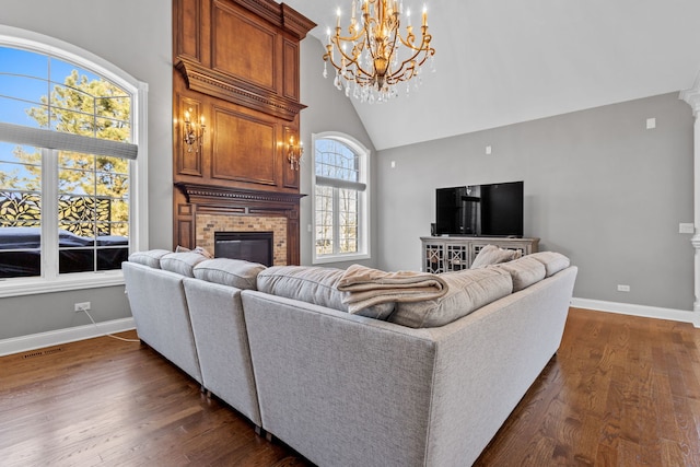 living room with a brick fireplace, dark hardwood / wood-style floors, high vaulted ceiling, and a notable chandelier