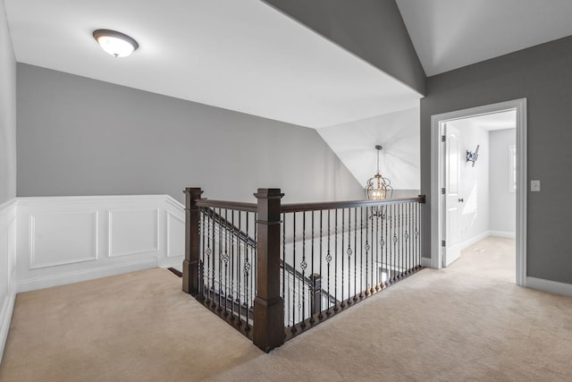 hall featuring vaulted ceiling, an inviting chandelier, and light carpet