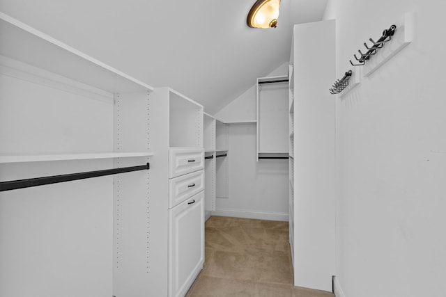 walk in closet with lofted ceiling and light colored carpet