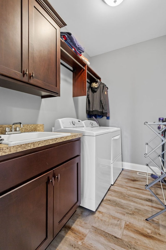 laundry room featuring washing machine and dryer, cabinets, and sink