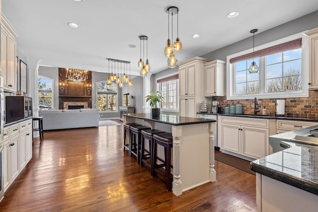 kitchen featuring a center island, decorative light fixtures, backsplash, dark hardwood / wood-style floors, and a breakfast bar area