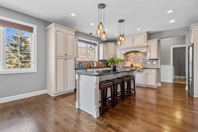 kitchen with a kitchen island, pendant lighting, a kitchen bar, sink, and dark hardwood / wood-style flooring