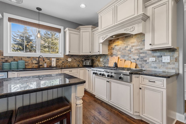 kitchen featuring tasteful backsplash, sink, dark stone countertops, and pendant lighting