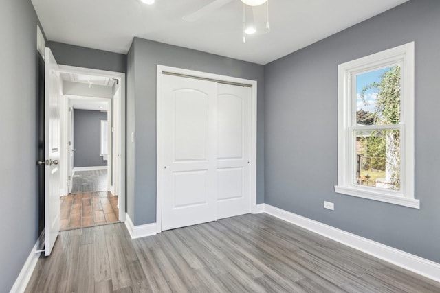 unfurnished bedroom featuring ceiling fan, a closet, and wood-type flooring