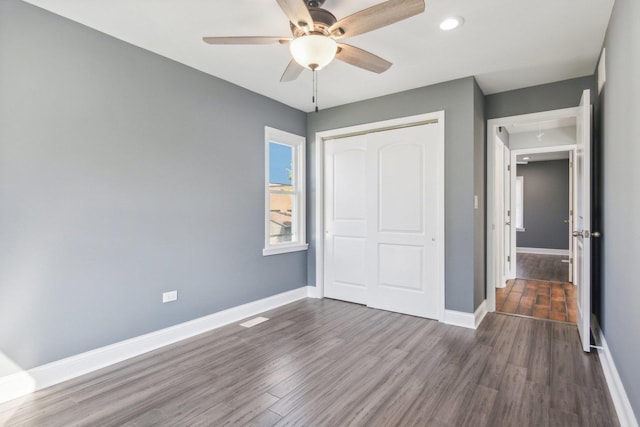 unfurnished bedroom with ceiling fan, dark hardwood / wood-style flooring, and a closet