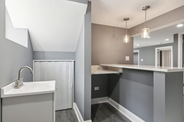 bathroom featuring hardwood / wood-style flooring, vaulted ceiling, and sink