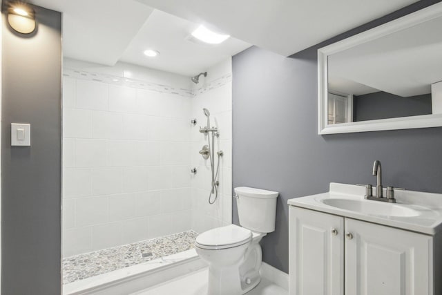 bathroom with tiled shower, vanity, and toilet