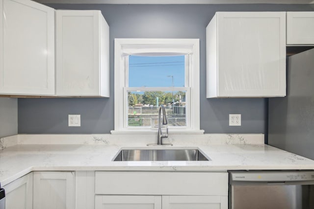 kitchen featuring dishwasher, sink, white cabinets, and light stone counters