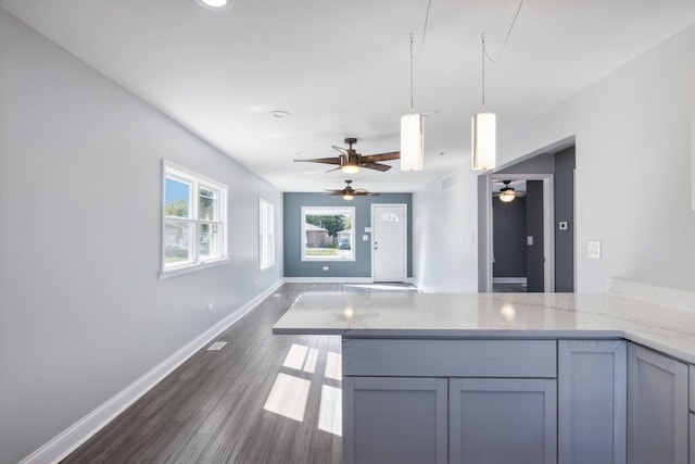 kitchen with pendant lighting, dark hardwood / wood-style floors, light stone counters, and gray cabinetry