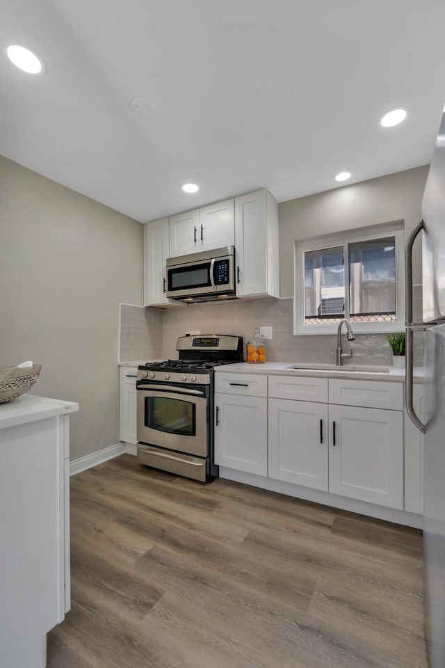 kitchen featuring white cabinetry, sink, stainless steel appliances, and light wood-type flooring