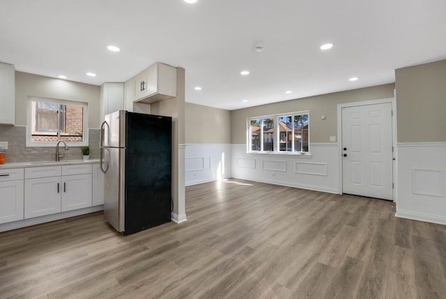 kitchen with white cabinetry, stainless steel fridge, sink, and light wood-type flooring