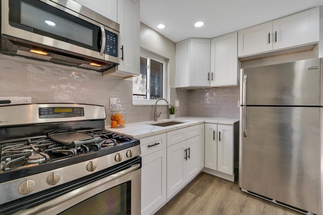 kitchen with white cabinets, light hardwood / wood-style floors, sink, and appliances with stainless steel finishes