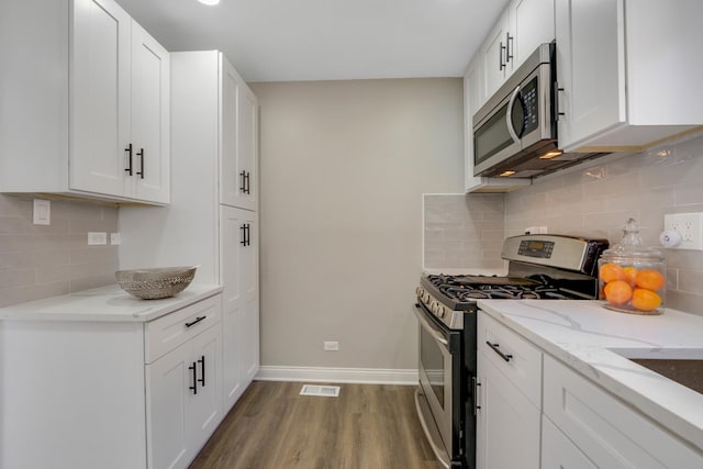 kitchen with white cabinets, appliances with stainless steel finishes, and hardwood / wood-style floors