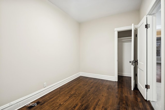 unfurnished bedroom featuring a closet and dark hardwood / wood-style floors