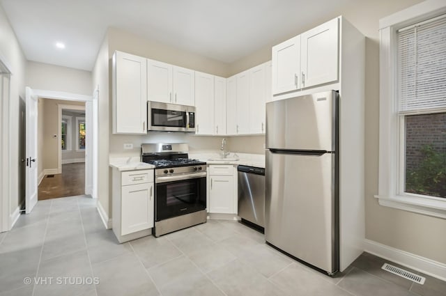 kitchen featuring appliances with stainless steel finishes, white cabinets, and sink