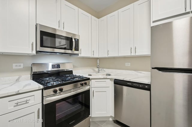 kitchen featuring light stone countertops, white cabinets, appliances with stainless steel finishes, and sink