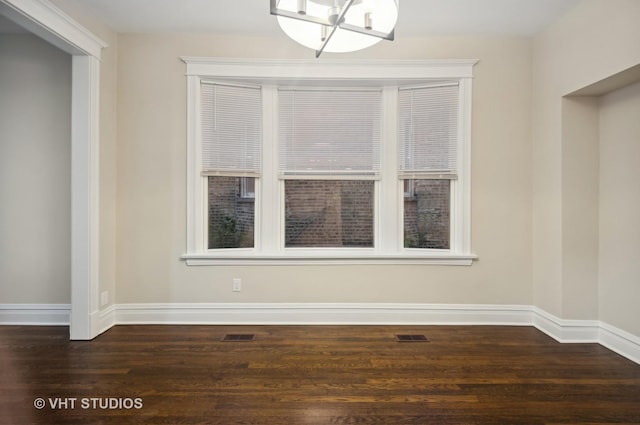 unfurnished dining area featuring dark hardwood / wood-style flooring and a chandelier